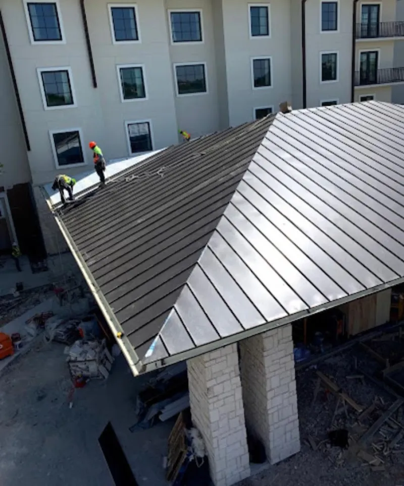 Crew installing standing seam metal roof panels on a commercial project in McCalla
